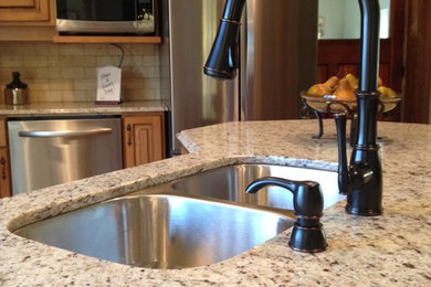 Eat-in kitchen - mid-sized country l-shaped medium tone wood floor eat-in kitchen idea in Toronto with a double-bowl sink, raised-panel cabinets, medium tone wood cabinets, granite countertops, beige backsplash, stone tile backsplash, stainless steel appliances and an island