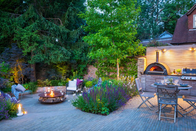 This is an example of a large classic back patio in Surrey with an outdoor kitchen, natural stone paving and a gazebo.