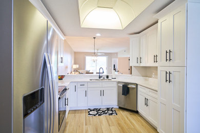 Example of a mid-sized minimalist u-shaped laminate floor and brown floor eat-in kitchen design in Other with a double-bowl sink, shaker cabinets, white cabinets, quartz countertops, white backsplash, quartz backsplash, stainless steel appliances, a peninsula and white countertops