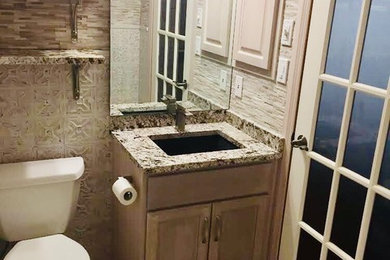 Mid-sized transitional gray tile bathroom photo in Other with recessed-panel cabinets, brown cabinets, a one-piece toilet, an undermount sink, granite countertops and gray countertops