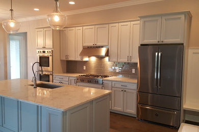 Example of a large galley light wood floor and brown floor eat-in kitchen design in Tampa with a drop-in sink, flat-panel cabinets, white cabinets, granite countertops, gray backsplash, ceramic backsplash, stainless steel appliances and an island