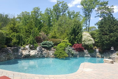 Large southwest backyard stone and custom-shaped natural pool fountain photo in New York