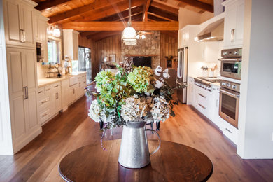 Inspiration for a mid-sized transitional galley dark wood floor eat-in kitchen remodel in San Francisco with a farmhouse sink, beaded inset cabinets, white cabinets, granite countertops, white backsplash, subway tile backsplash, stainless steel appliances and an island