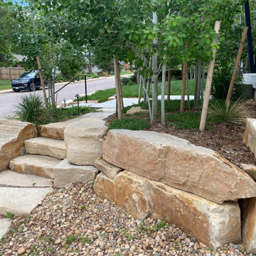Mountain inspired minimalist boulder retaining walls and plantings.