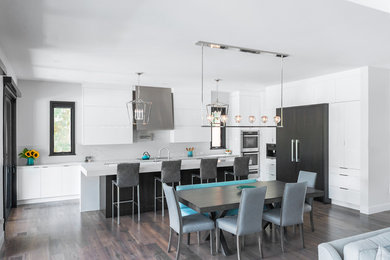 Inspiration for an expansive contemporary l-shaped open plan kitchen in Toronto with an undermount sink, flat-panel cabinets, dark wood cabinets, quartzite benchtops, white splashback, stone slab splashback, panelled appliances, medium hardwood floors, with island and brown floor.