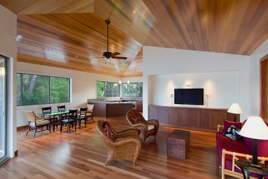 Photo of a mid-sized beach style formal open concept living room in Hawaii with white walls, medium hardwood floors, no fireplace, a wall-mounted tv and brown floor.