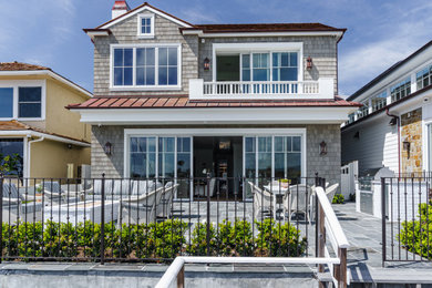 Inspiration for a large coastal gray two-story shingle house exterior remodel in Orange County with a red roof and a metal roof