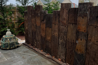 This is an example of a medium sized rustic back garden in Cornwall with a retaining wall and a wood fence.