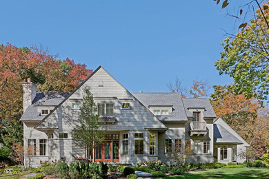 Photo of a large arts and crafts two-storey grey exterior in Chicago with wood siding and a gable roof.