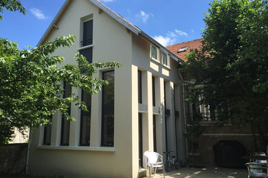 Ejemplo de fachada de casa pareada beige actual de tamaño medio de dos plantas con revestimientos combinados, tejado a dos aguas y tejado de teja de barro