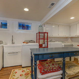 サンタバーバラの大きいトランジショナルスタイルのおしゃれな家事室 (スロップシンク、落し込みパネル扉のキャビネット、白いキャビネット、木材カウンター、ベージュの壁、無垢フローリング、左右配置の洗濯機・乾燥機、茶色い床、赤いキッチンカウンター) の写真