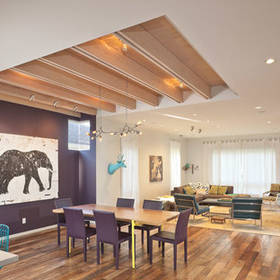 Idée de décoration pour une salle à manger ouverte sur le salon design avec un mur violet et un sol en bois brun.