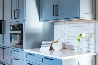 Kitchen - mid-sized transitional u-shaped light wood floor and brown floor kitchen idea in Seattle with shaker cabinets, gray cabinets, quartzite countertops, white backsplash, subway tile backsplash, stainless steel appliances, a peninsula and white countertops