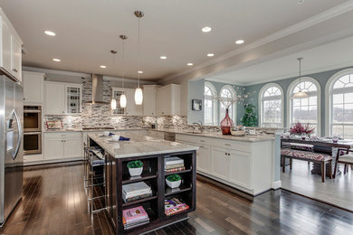 Large transitional u-shaped open plan kitchen in DC Metro with an undermount sink, shaker cabinets, white cabinets, granite benchtops, multi-coloured splashback, matchstick tile splashback, stainless steel appliances, laminate floors and with island.