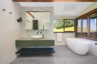 Photo of an eclectic master bathroom in Gold Coast - Tweed with green cabinets, a freestanding tub, an alcove shower, white tile, porcelain tile, porcelain floors, engineered quartz benchtops, grey floor, an open shower, grey benchtops, a single vanity and a floating vanity.