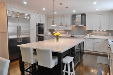 Mid-sized transitional l-shaped medium tone wood floor eat-in kitchen photo in DC Metro with a drop-in sink, raised-panel cabinets, white cabinets, solid surface countertops, gray backsplash, subway tile backsplash, stainless steel appliances and an island