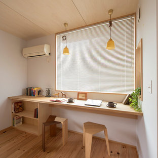 Immagine di uno studio etnico con pareti bianche, pavimento in legno massello medio, scrivania incassata e pavimento marrone