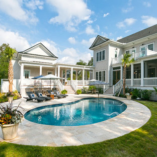 Exempel på en maritim njurformad pool på baksidan av huset, med naturstensplattor