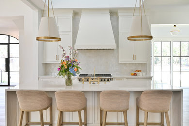 Cette image montre une cuisine américaine design avec parquet clair et un sol marron.