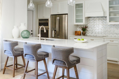 Open concept kitchen - contemporary galley light wood floor and beige floor open concept kitchen idea in Jacksonville with an undermount sink, shaker cabinets, white cabinets, multicolored backsplash, stainless steel appliances, a peninsula, white countertops, solid surface countertops and matchstick tile backsplash