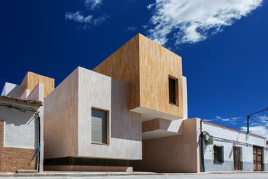 Foto de fachada de casa beige actual de tres plantas con revestimiento de piedra, tejado plano y tejado de varios materiales