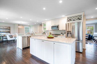 Inspiration for a large transitional l-shaped laminate floor and brown floor eat-in kitchen remodel in DC Metro with a double-bowl sink, shaker cabinets, white cabinets, quartz countertops, green backsplash, glass sheet backsplash, stainless steel appliances, an island and white countertops