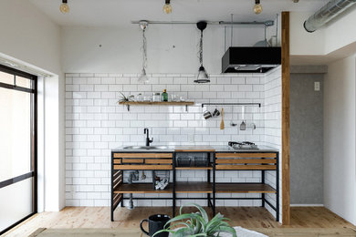 Industrial single-wall open plan kitchen in Nagoya with an integrated sink, open cabinets, stainless steel benchtops, white splashback, subway tile splashback, stainless steel appliances and medium hardwood floors.