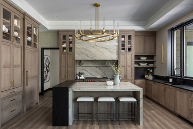 Example of a transitional brown floor and tray ceiling eat-in kitchen design in Detroit with an undermount sink, shaker cabinets, medium tone wood cabinets, quartzite countertops, gray backsplash, quartz backsplash, paneled appliances, an island and gray countertops