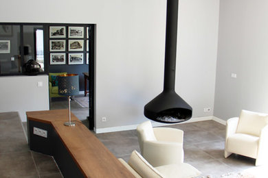 Inspiration for a large contemporary formal enclosed living room in Toulouse with white walls, porcelain floors, a hanging fireplace, a metal fireplace surround, no tv and grey floor.
