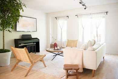 Ejemplo de sala de estar abierta minimalista de tamaño medio con paredes blancas, suelo laminado, televisor colgado en la pared y suelo beige