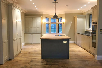 This is an example of a country kitchen in Devon with a submerged sink, shaker cabinets and an island.