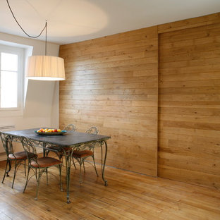 Cette image montre une salle à manger design fermée et de taille moyenne avec un mur blanc, un sol en bois brun et aucune cheminée.