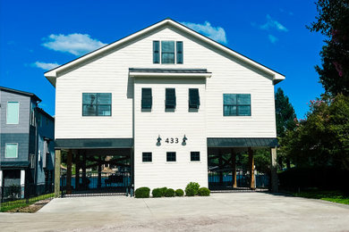 Beach style white two-story concrete fiberboard and board and batten house exterior photo in Austin with a black roof