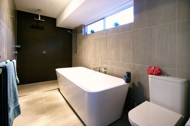 Inspiration for a large contemporary bathroom in Brisbane with a freestanding tub, a wall-mount toilet, green tile, porcelain tile, grey walls, porcelain floors and with a sauna.