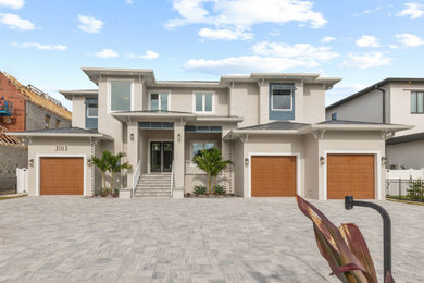 Example of a transitional beige two-story stucco house exterior design in Tampa with a metal roof