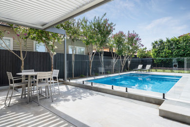 This is an example of a large beach style backyard rectangular pool in Melbourne with a hot tub and natural stone pavers.