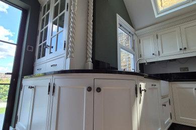 Inspiration for a large classic l-shaped open plan kitchen in London with shaker cabinets, beige cabinets, granite worktops, green splashback, stainless steel appliances, dark hardwood flooring, an island, brown floors, black worktops and a vaulted ceiling.