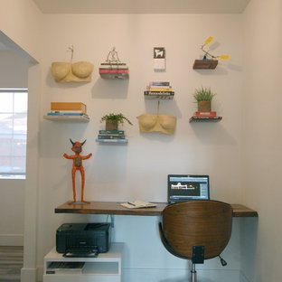 Small modern study in Los Angeles with white walls, bamboo flooring, a built-in desk and grey floors.