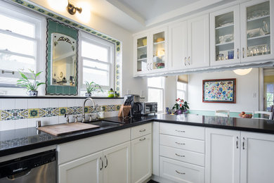 Example of a mid-sized classic u-shaped vinyl floor eat-in kitchen design in Los Angeles with an undermount sink, white cabinets, quartz countertops, multicolored backsplash, ceramic backsplash, stainless steel appliances, a peninsula and glass-front cabinets
