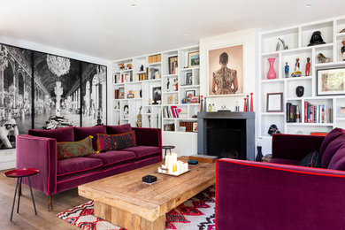 This is an example of an eclectic open concept living room in London with white walls, dark hardwood floors, a standard fireplace and brown floor.