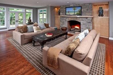 Mid-sized transitional formal open concept living room in Philadelphia with grey walls, medium hardwood floors, a standard fireplace, a stone fireplace surround, a wall-mounted tv and brown floor.