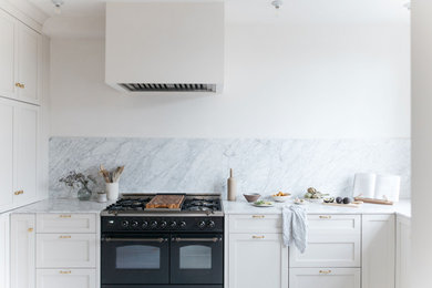 Example of a small french country u-shaped painted wood floor kitchen design in Vancouver with a farmhouse sink, shaker cabinets, white cabinets, white backsplash, quartz backsplash, no island, white countertops, quartz countertops and paneled appliances