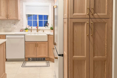 Enclosed kitchen - mid-sized transitional l-shaped porcelain tile and gray floor enclosed kitchen idea in Boston with a farmhouse sink, shaker cabinets, light wood cabinets, quartz countertops, gray backsplash, ceramic backsplash, white appliances, a peninsula and white countertops