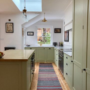 Light green cottage style kitchen with white worktops and kitchen island