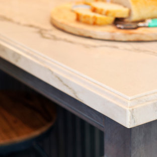 Cette photo montre une grande arrière-cuisine chic en U avec un placard à porte shaker, des portes de placard grises, un plan de travail en quartz, un sol en bois foncé et un îlot central.