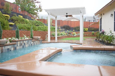 Mid-sized traditional backyard rectangular pool in Sacramento with stamped concrete and a hot tub.