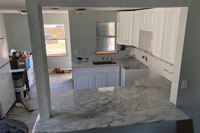 Inspiration for a small transitional u-shaped laminate floor and gray floor eat-in kitchen remodel in Tampa with an undermount sink, raised-panel cabinets, white cabinets, granite countertops, a peninsula and white countertops
