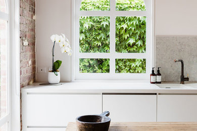 This is an example of a mid-sized contemporary l-shaped eat-in kitchen in Melbourne with an undermount sink, raised-panel cabinets, white cabinets, quartz benchtops, white splashback, mosaic tile splashback, stainless steel appliances, concrete floors, with island and white floor.