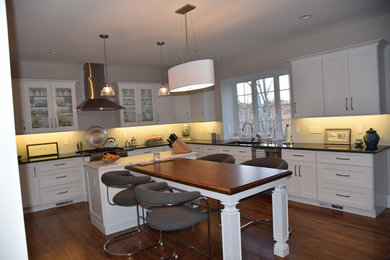 Photo of a mid-sized transitional l-shaped eat-in kitchen in Bridgeport with an undermount sink, shaker cabinets, white cabinets, quartz benchtops, dark hardwood floors, with island, brown floor and black benchtop.