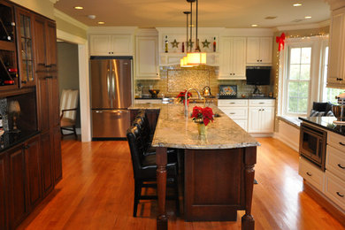 Inspiration for a timeless u-shaped medium tone wood floor kitchen remodel in New York with an undermount sink, raised-panel cabinets, white cabinets, granite countertops, green backsplash, glass tile backsplash, stainless steel appliances and an island